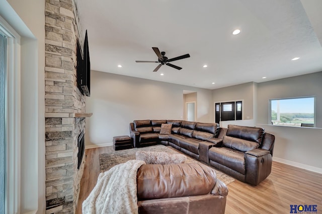 living area featuring a stone fireplace, light wood finished floors, and recessed lighting