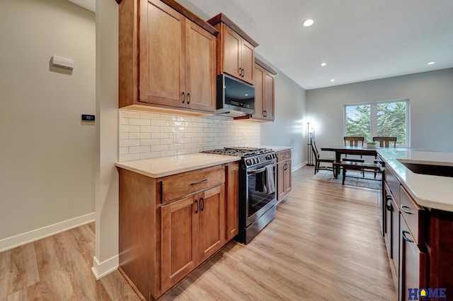 kitchen featuring stainless steel appliances, baseboards, light wood-style floors, backsplash, and brown cabinetry