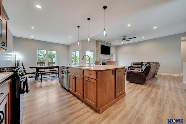 kitchen featuring black gas range, a kitchen island with sink, a sink, open floor plan, and light countertops