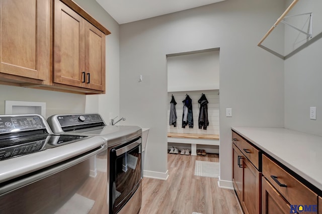 laundry area featuring baseboards, washing machine and dryer, cabinet space, and light wood-style floors