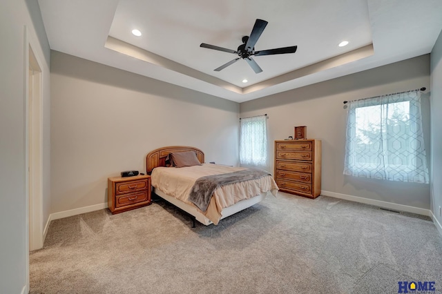 bedroom featuring baseboards, a raised ceiling, and light colored carpet