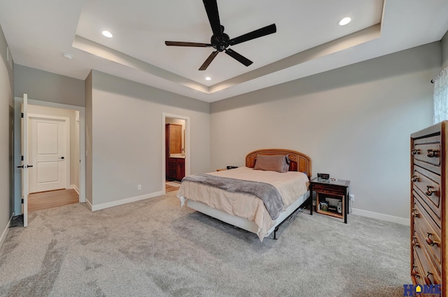 bedroom featuring baseboards, a tray ceiling, recessed lighting, and light colored carpet