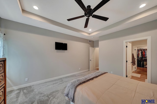 bedroom with a tray ceiling, recessed lighting, and baseboards