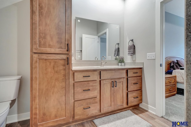 ensuite bathroom with baseboards, toilet, vanity, and ensuite bath