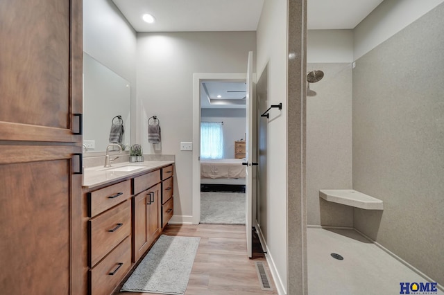 ensuite bathroom with visible vents, ensuite bathroom, vanity, wood finished floors, and walk in shower