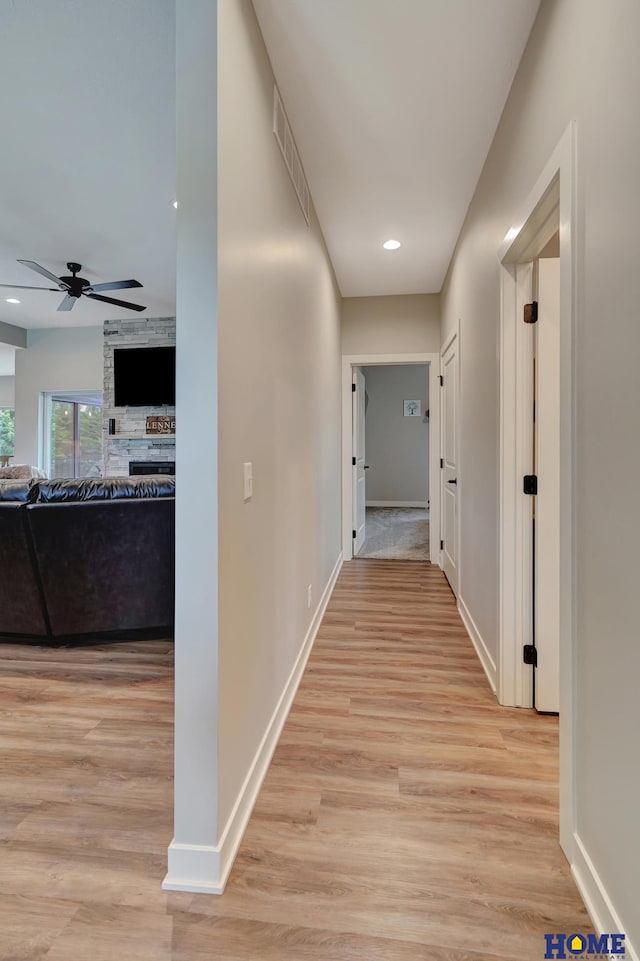 corridor featuring light wood-type flooring, visible vents, baseboards, and recessed lighting