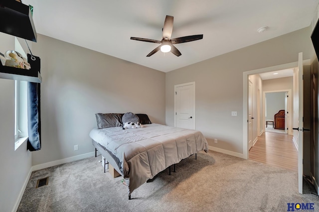 bedroom featuring a ceiling fan, light carpet, visible vents, and baseboards