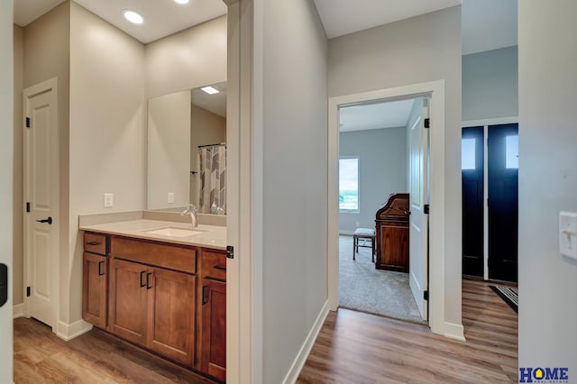 full bath with baseboards, wood finished floors, and vanity