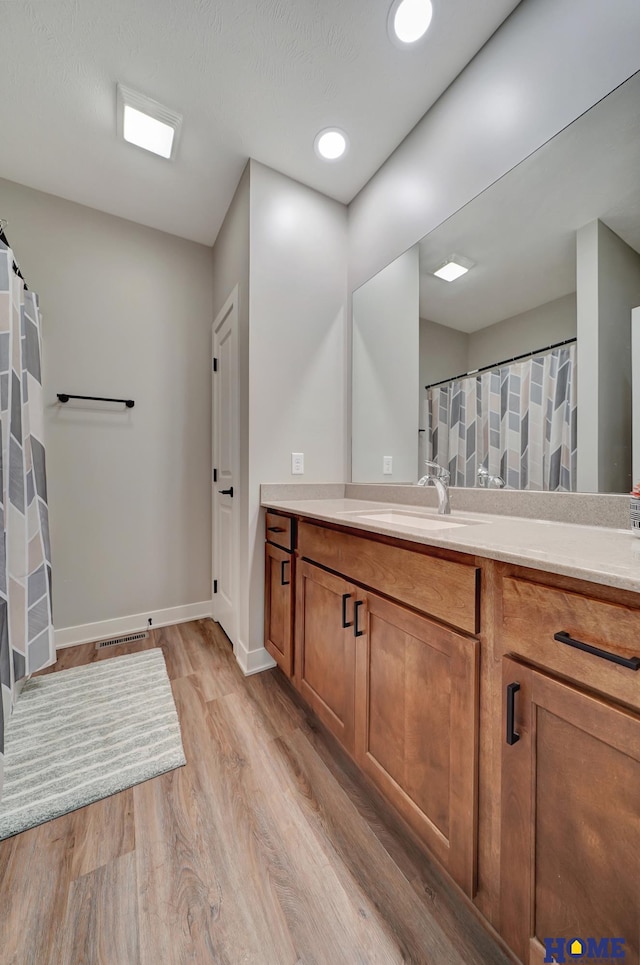 full bath with visible vents, baseboards, wood finished floors, vanity, and recessed lighting