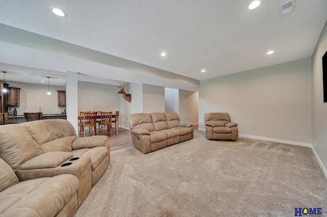 living room with recessed lighting, visible vents, light carpet, and baseboards