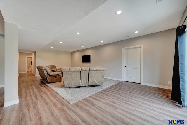 living room featuring light wood-type flooring, baseboards, a textured ceiling, and recessed lighting