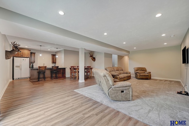 living area featuring recessed lighting, baseboards, and light wood finished floors