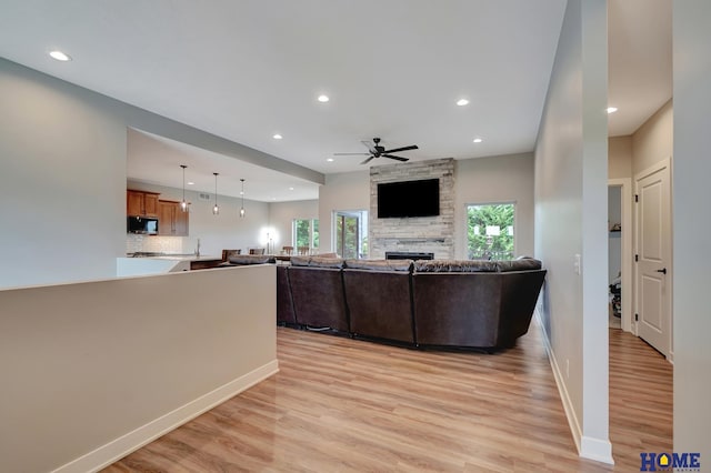 unfurnished living room with light wood finished floors, a wealth of natural light, and a stone fireplace