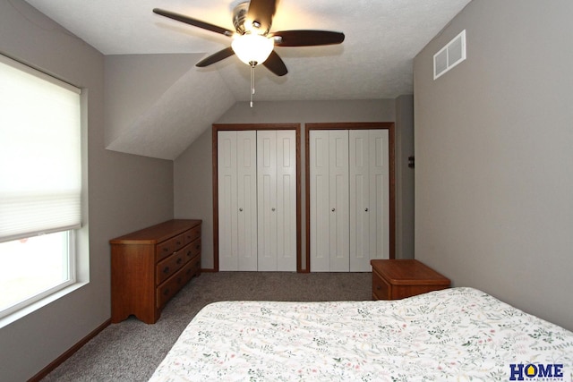 bedroom featuring ceiling fan, carpet floors, visible vents, multiple closets, and vaulted ceiling