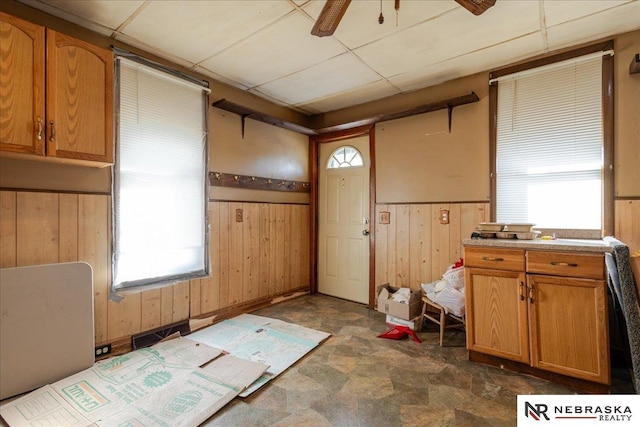 kitchen with a wainscoted wall, light countertops, wood walls, and a drop ceiling