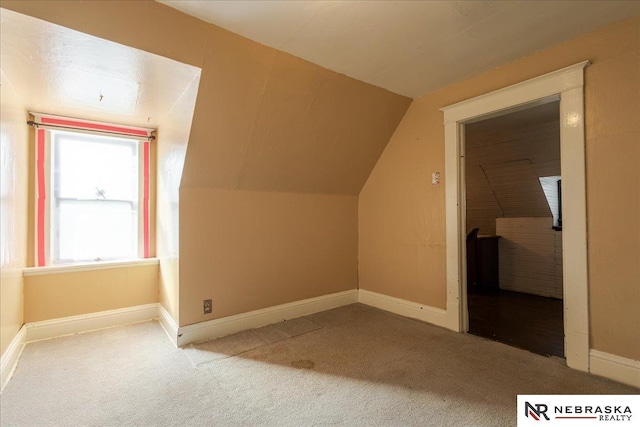 bonus room featuring lofted ceiling, baseboards, and light colored carpet