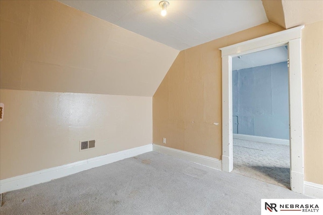 additional living space with light colored carpet, visible vents, vaulted ceiling, and baseboards