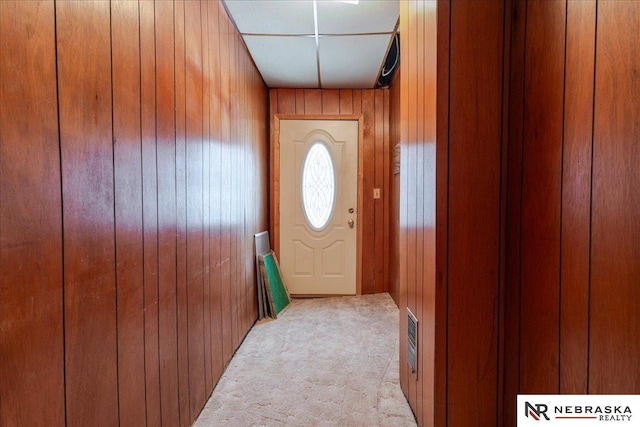 entryway with light carpet and wood walls