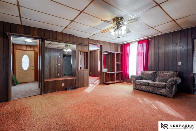 unfurnished living room featuring wood walls, carpet, visible vents, and ceiling fan