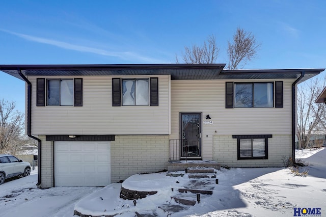 raised ranch with an attached garage and brick siding