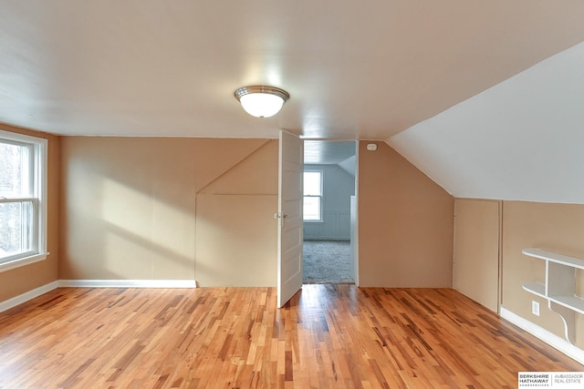 bonus room featuring light wood-type flooring, visible vents, and vaulted ceiling