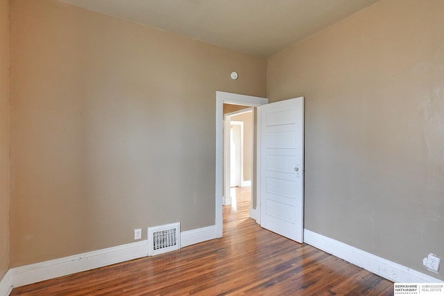 spare room featuring visible vents, baseboards, and wood finished floors