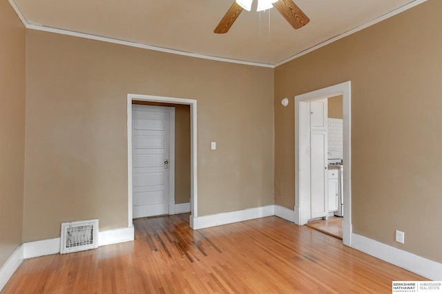 empty room with baseboards, ornamental molding, visible vents, and light wood-style floors