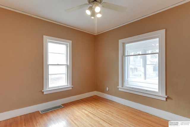 unfurnished room with a ceiling fan, visible vents, baseboards, ornamental molding, and light wood finished floors