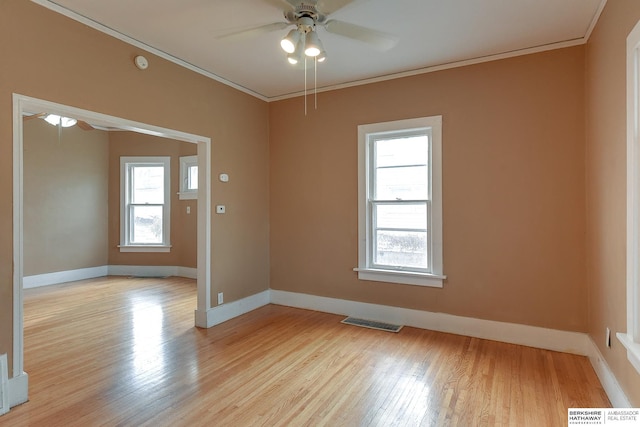 empty room with ornamental molding, a healthy amount of sunlight, and visible vents