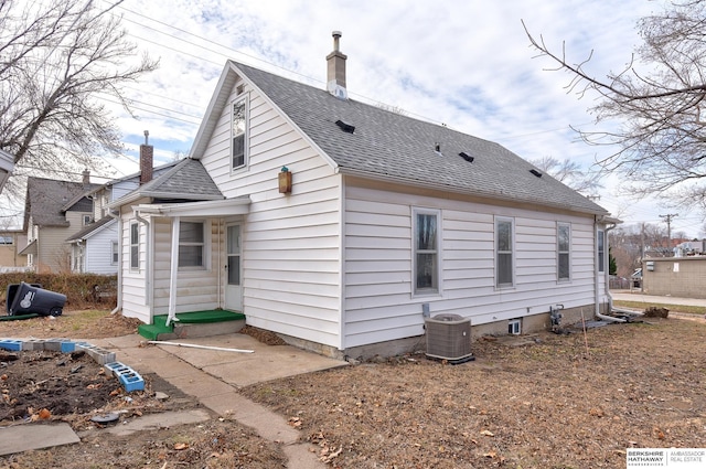 view of home's exterior with central air condition unit, a shingled roof, and a chimney