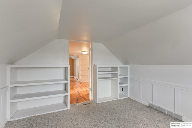 additional living space with light carpet, vaulted ceiling, and visible vents