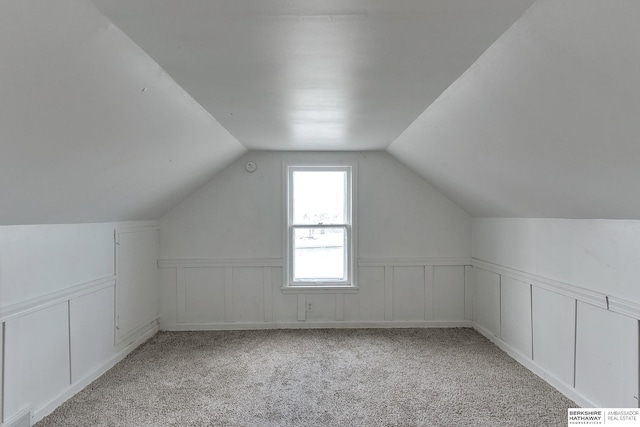 bonus room with light carpet, visible vents, vaulted ceiling, and wainscoting