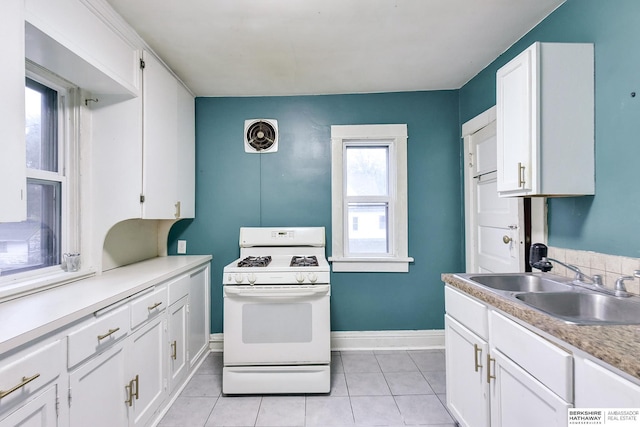 kitchen with a sink, white gas stove, light countertops, and white cabinetry