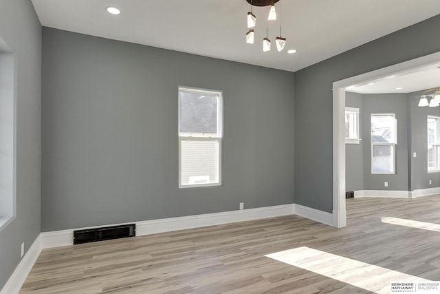 empty room featuring baseboards, visible vents, light wood-style flooring, a notable chandelier, and recessed lighting