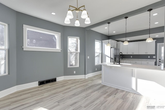 kitchen featuring white cabinets, light countertops, hanging light fixtures, and visible vents