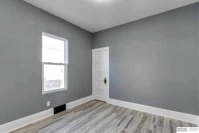 spare room featuring visible vents, light wood-style flooring, and baseboards