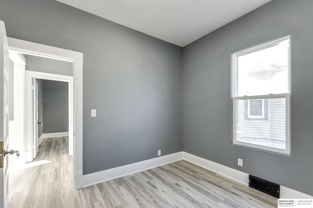 empty room featuring light wood-type flooring, visible vents, and baseboards