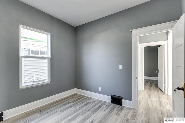 unfurnished room with light wood-style floors, visible vents, and baseboards