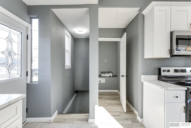 kitchen with baseboards, white cabinetry, appliances with stainless steel finishes, and light stone counters