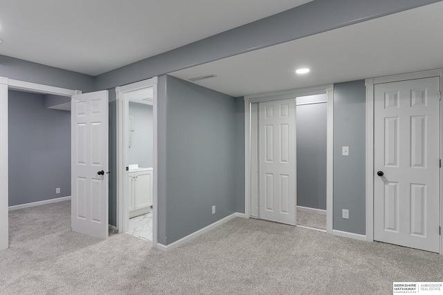 unfurnished bedroom featuring ensuite bath, visible vents, baseboards, and light colored carpet