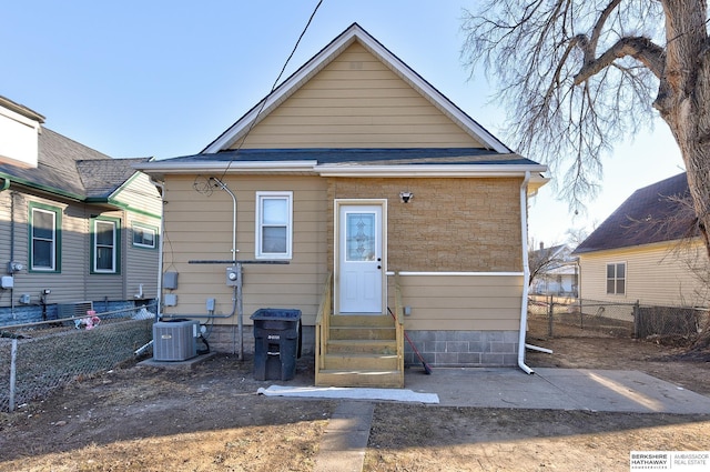 rear view of house featuring entry steps, fence, and central AC unit