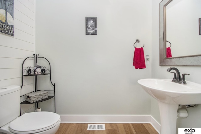 bathroom with toilet, baseboards, visible vents, and wood finished floors