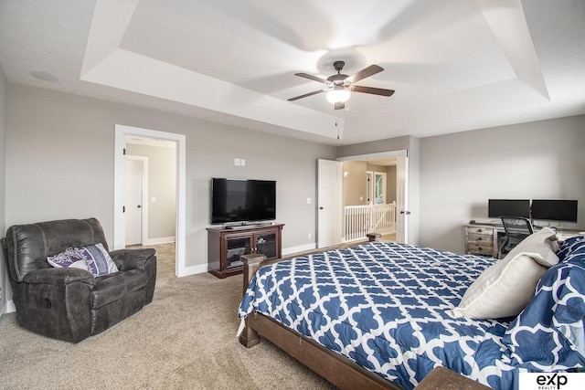 carpeted bedroom featuring a raised ceiling, a ceiling fan, and baseboards