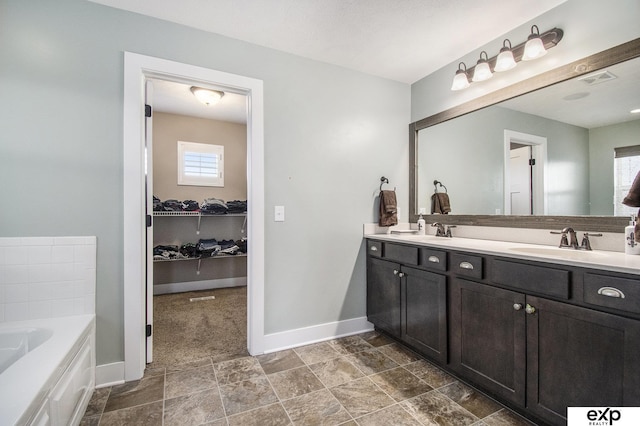 bathroom featuring double vanity, baseboards, a sink, and a bath