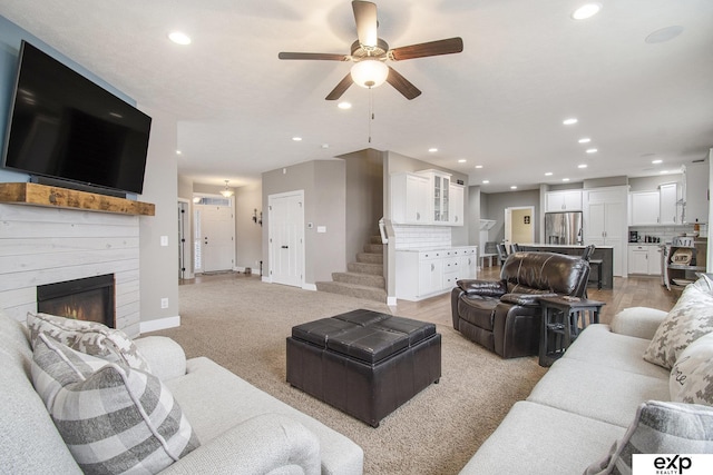 living room with recessed lighting, a glass covered fireplace, stairway, and baseboards