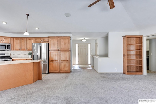 kitchen featuring light carpet, decorative backsplash, stainless steel appliances, light countertops, and pendant lighting