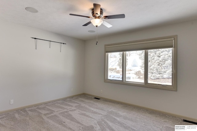 empty room with light carpet, baseboards, visible vents, ceiling fan, and a textured ceiling