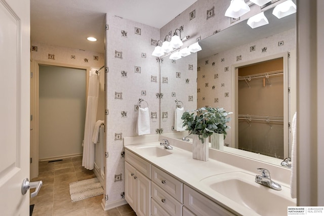 bathroom featuring double vanity, wallpapered walls, tile patterned flooring, and a sink