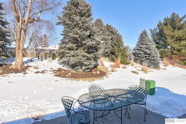 snow covered patio with outdoor dining area and fence