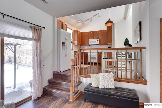 staircase with vaulted ceiling, wood finished floors, and track lighting